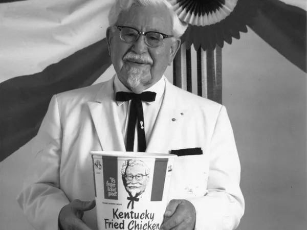 Полковник Харланд Сандърс държи кофа KFC